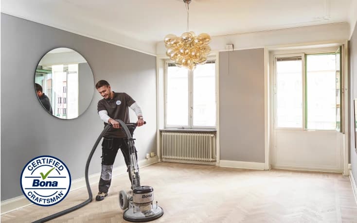 Operario puliendo con equipo Bona el piso de madera de una sala.